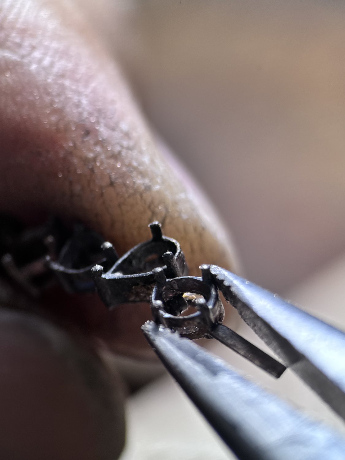 Hand setting small stones into a jewelry piece under magnification